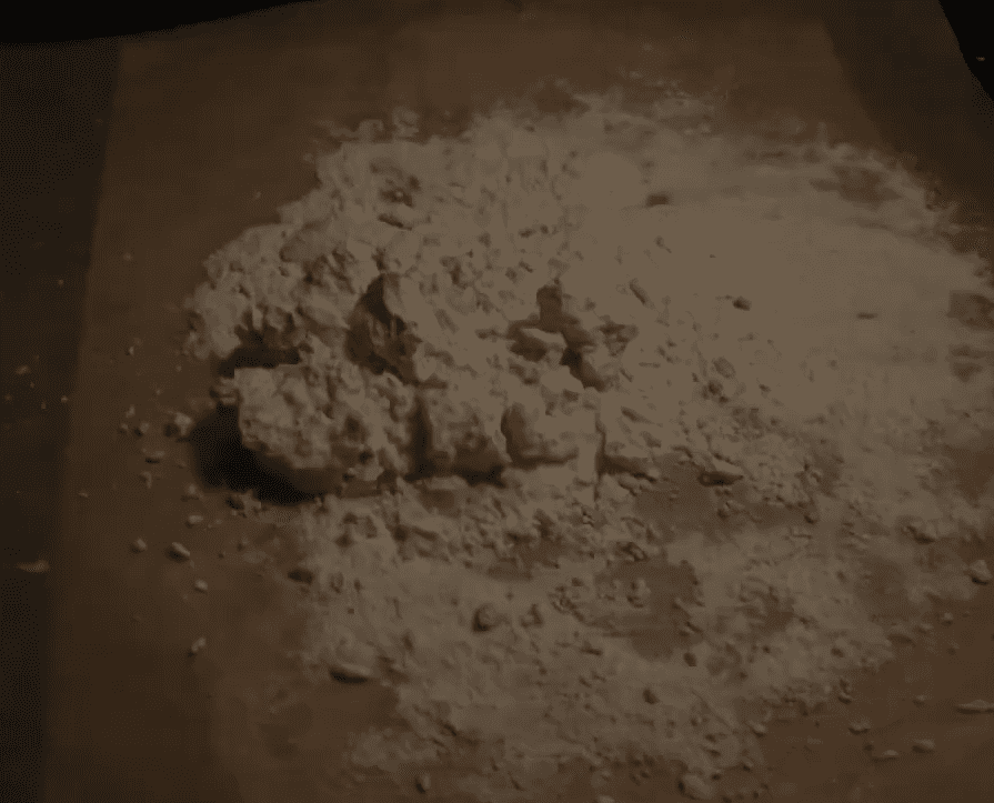 a mound of white powder scattered on a brown surface with some clumps and grains visible the lighting is dim casting shadows around the edges of the pile digital production A mound of white powder scattered on a brown surface, with some clumps and grains visible. The lighting is dim, casting shadows around the edges of the pile.