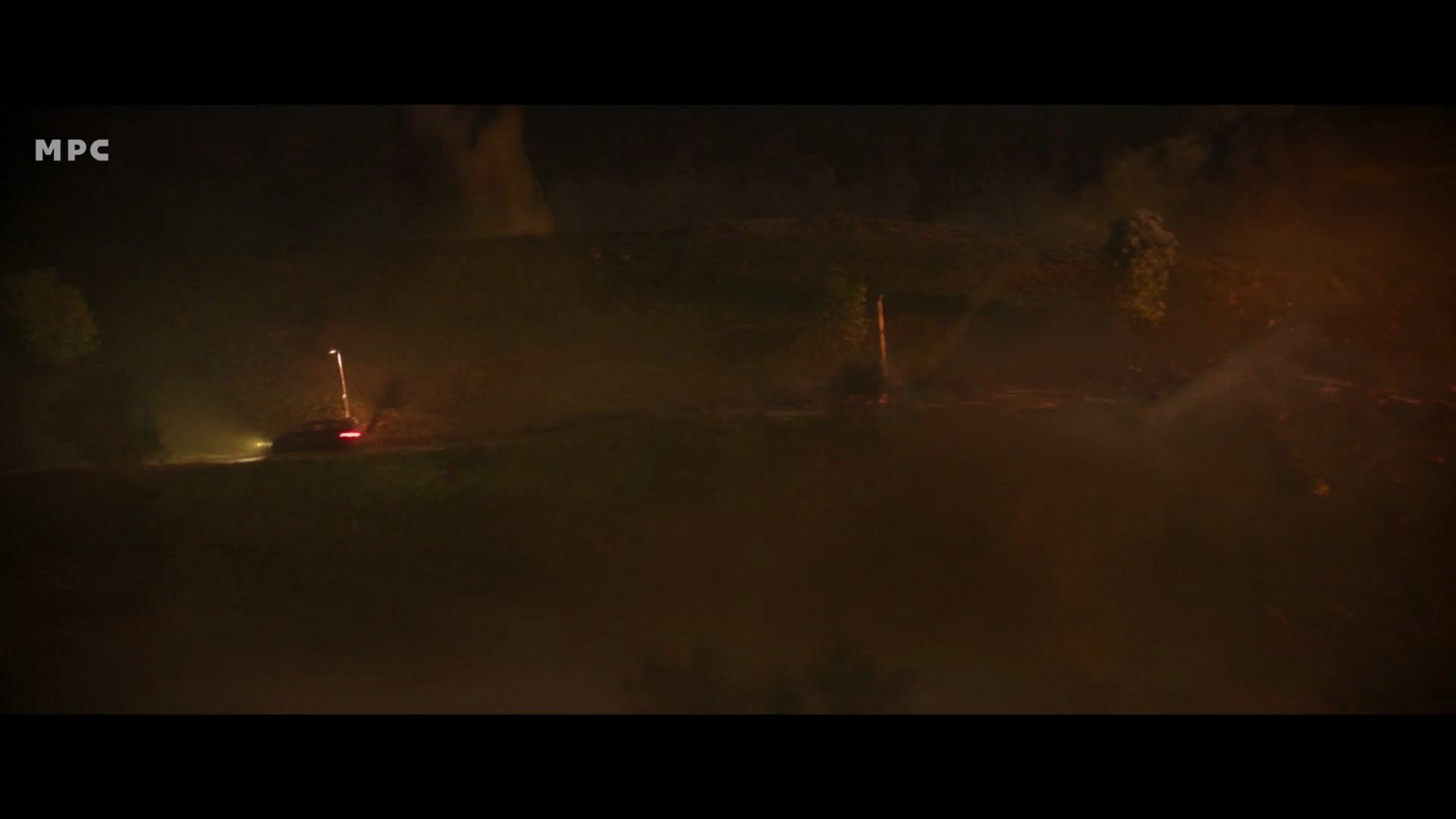 a nighttime scene featuring a car parked on a hillside illuminated by its headlights a faint glow from a distant structure and swirling mist create a mysterious atmosphere dark trees and rugged terrain are visible in the background digital production A nighttime scene featuring a car parked on a hillside, illuminated by its headlights. A faint glow from a distant structure and swirling mist create a mysterious atmosphere. Dark trees and rugged terrain are visible in the background.