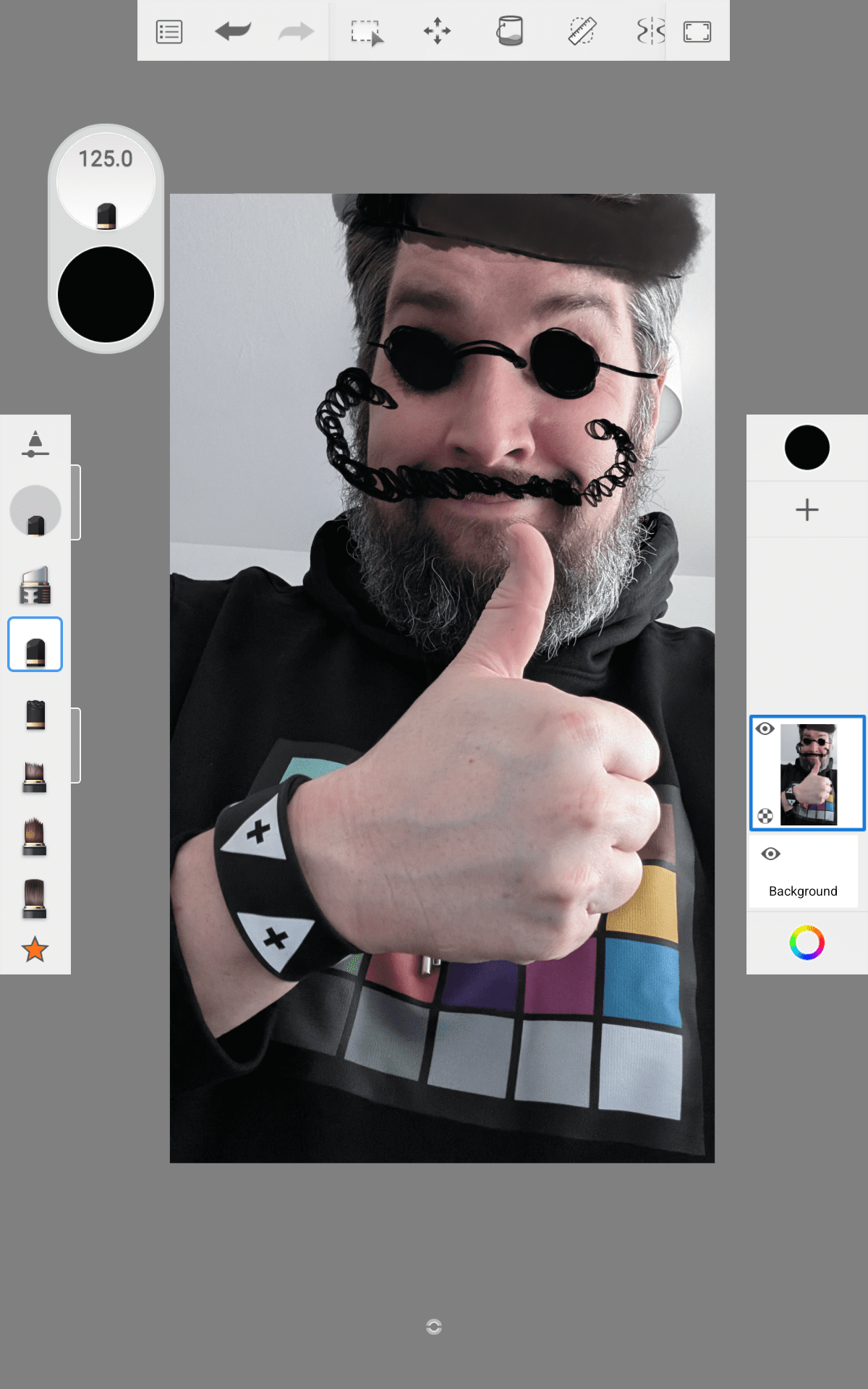 a person with a beard wearing a black hoodie featuring a colorful graphic giving a thumbsup gesture the image includes playful digital effects like a hat and mustache drawn on digital production A person with a beard wearing a black hoodie featuring a colorful graphic, giving a thumbs-up gesture. The image includes playful digital effects like a hat and mustache drawn on.