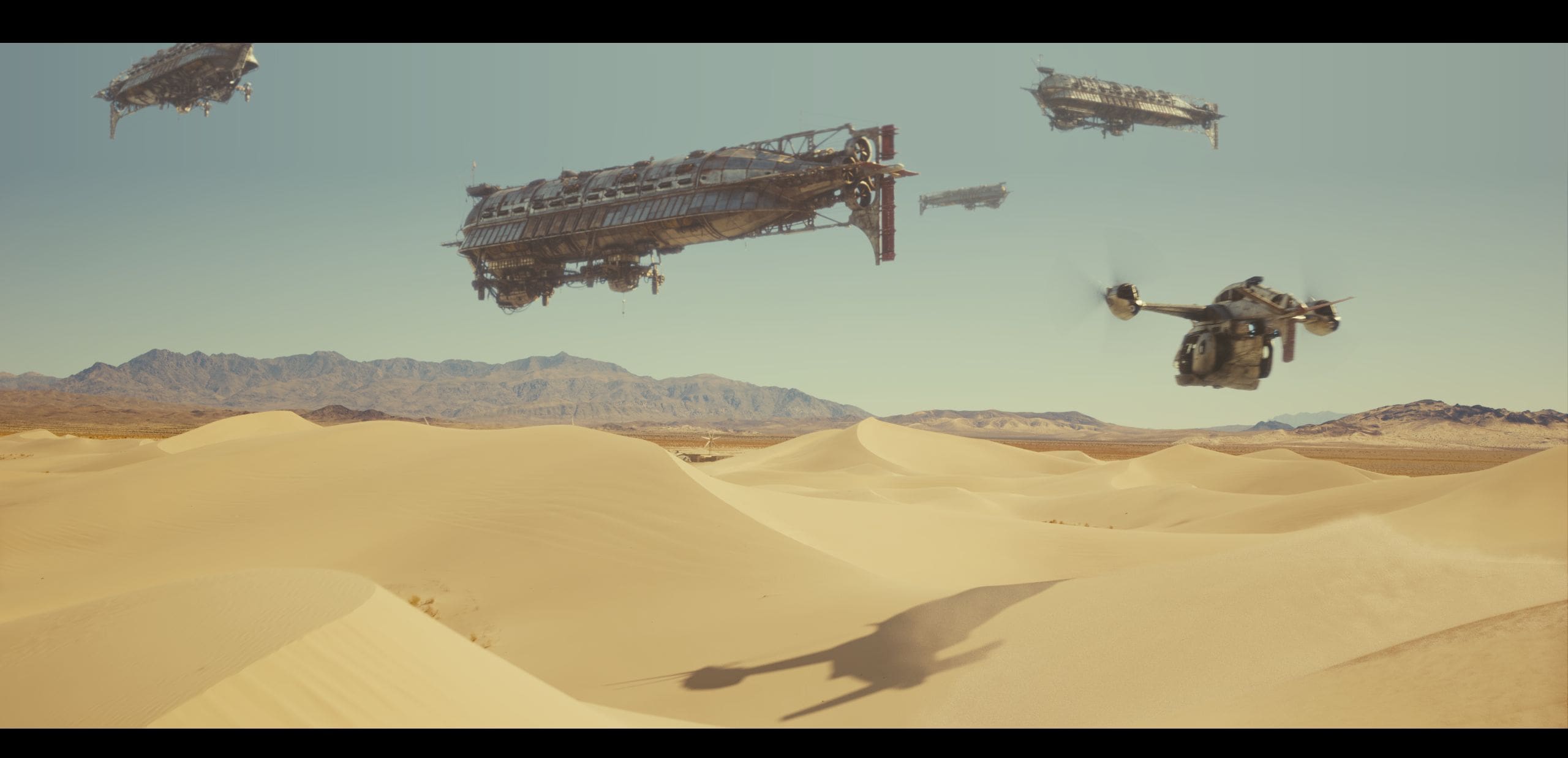 a vast desert landscape features rolling golden sand dunes under a clear sky in the distance large futuristic ships float serenely above the ground while a smaller aircraft hovers nearby casting a shadow onto the dunes digital production A vast desert landscape features rolling golden sand dunes under a clear sky. In the distance, large futuristic ships float serenely above the ground, while a smaller aircraft hovers nearby, casting a shadow onto the dunes.