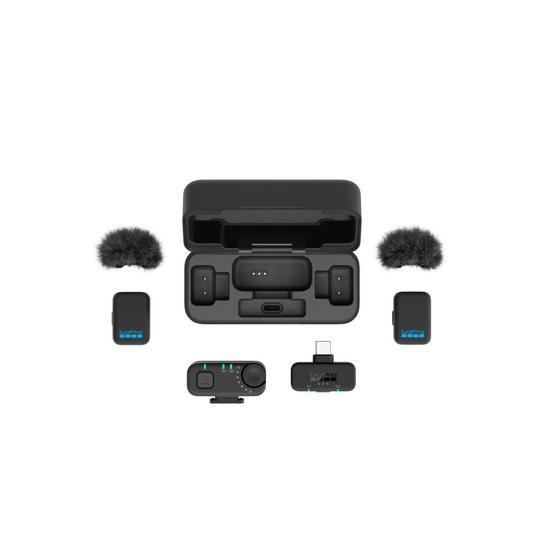 a compact and sleek black audio equipment set arranged neatly the centerpiece is a charging case housing two wireless microphones with small furry windshields flanking the case are two transmitters each with a blue display and a receiver with a control panel all designed for seamless audio capture digital production A compact and sleek black audio equipment set arranged neatly. The centerpiece is a charging case, housing two wireless microphones with small furry windshields. Flanking the case are two transmitters, each with a blue display, and a receiver with a control panel, all designed for seamless audio capture.